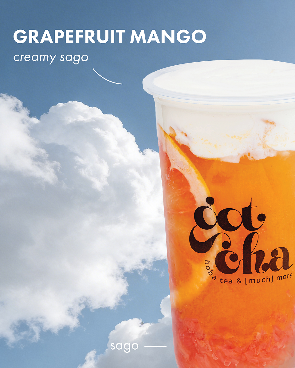 Grapefruit mango creamy sago boba tea in clear plastic cup with cloudy blue sky background.