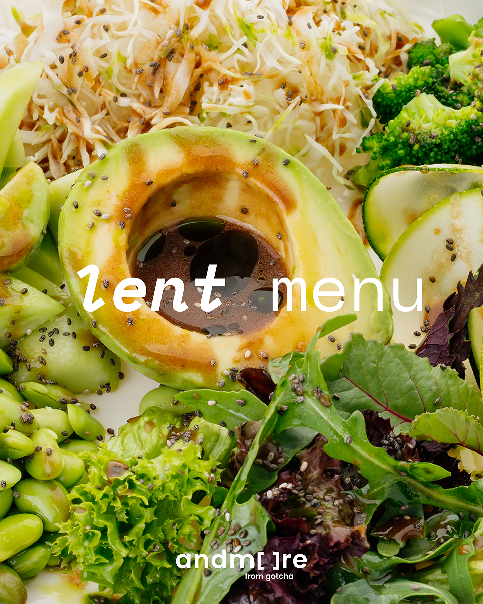 Half an avocado with balsamic glaze surrounded by assorted fresh green vegetables and chia seeds.