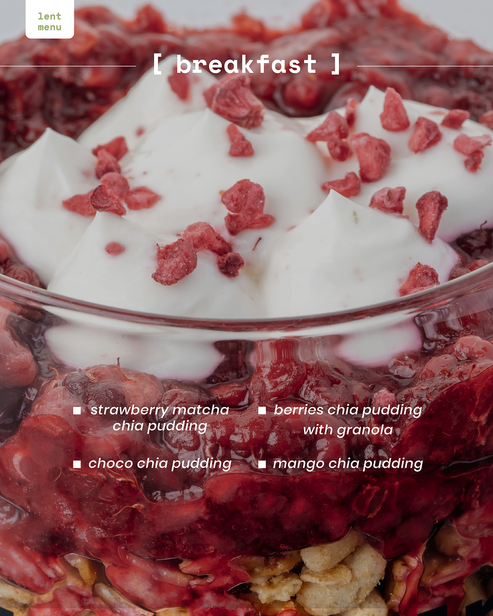 Close-up of chia pudding topped with white cream and red berry pieces in a glass container.